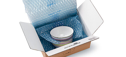 
				Ein Produkt ist in Luftpolsterfolie in einem Karton verpackt.