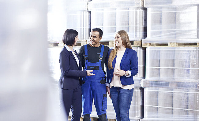 Two women and a man talking in a warehouse