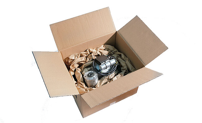 A cardboard box containing a component and brown paper cushioning