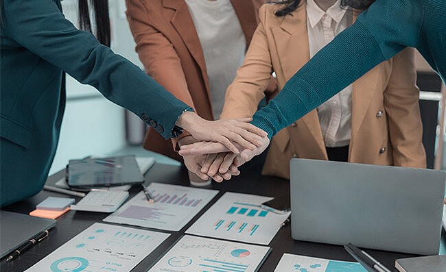 Business team stacking hands, symbolizing teamwork and collaboration.
