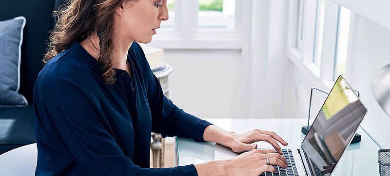 
		  A woman in an office sitting at her laptop