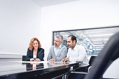 
			Two men and a woman having a meeting in a conference room, documents are on the table in front of them