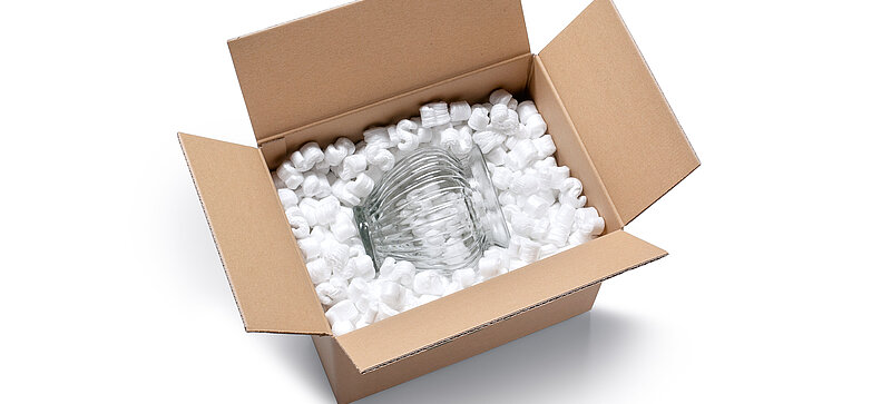 
		  A cardboard box containing a glass vase and S-shaped white packaging chips