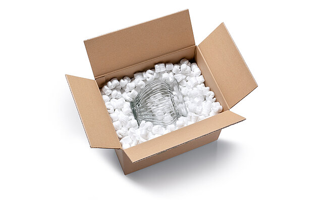 A cardboard box containing a glass vase and S-shaped white packaging chips