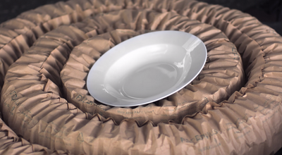 
				Ein Teller wird von einem braunen Papierpolsterstrang umwickelt und gepolstert. 