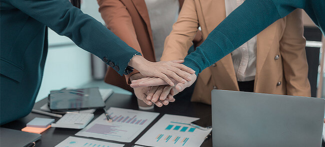 
			Business team stacking hands, symbolizing teamwork and collaboration.