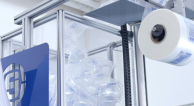 
				In einer großen durchsichtigen Box befinden sich mehrere Luftpolster und ganz rechts befindet sich eine Luftpolsterfolienrolle. 