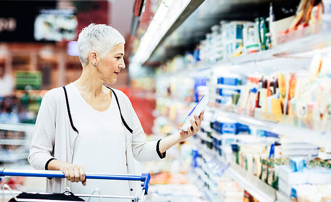 A woman standing in front of the chilled goods section in the supermarket